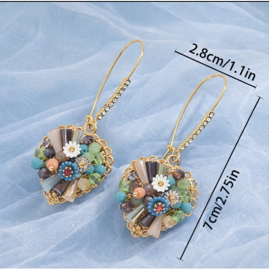 Artystyczne kolczyki w złotym kolorze, zdobione kolorowymi kamieniami i kwiatowymi detalami – biżuteria o wyjątkowym, rękodzielniczym charakterze.